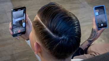 Un hombre filma con su móvil mientras asiste a una campaña electoral de la AfD en Neu Isenburg, cerca de Fráncfort, 1 de febrero de 2025.